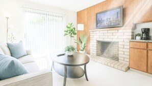 A modern living room with a sofa, a round coffee table, a fireplace, and a television mounted on the wall. - Spacious 3 BR 2B House Sunnyvale Park (Sunnyvale)
