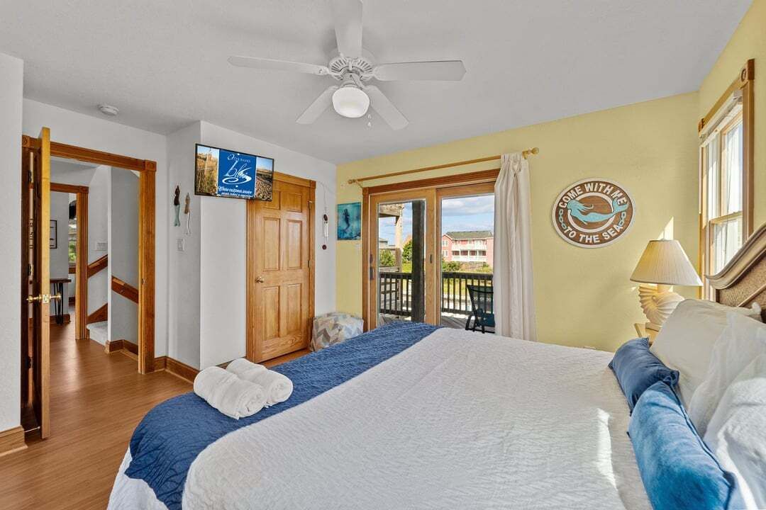 Une chambre d’hôtel avec un lit, un ventilateur de plafond, une vue sur l’extérieur et un panneau accroché au mur.