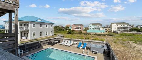 A swimming pool with lounge chairs, a wooden deck, and a view of surrounding buildings.