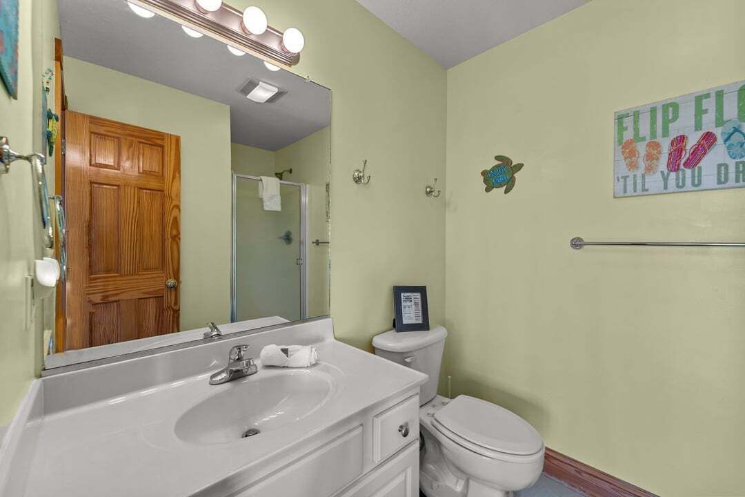 Une salle de bain équipée d’un lavabo, d’un miroir, de toilettes et d’un panneau mural.