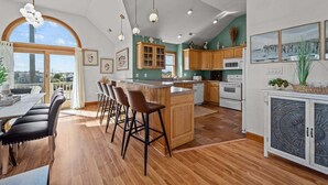 A spacious kitchen with wooden cabinets, a large island with bar stools, and a dining area with a table and chairs.