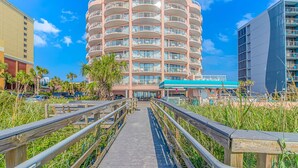 A multi-story hotel with balconies, a covered walkway, and a parking area. - St Clements 704 (Myrtle Beach)