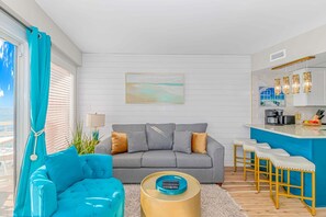 A living room with a sofa, a coffee table, and a bar area with stools.