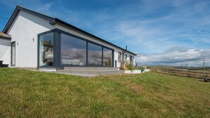 A modern house with large glass windows, a flat roof, and a grassy yard.
