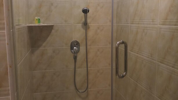 Un espace douche équipé d’un pommeau de douche à main et d’un robinet mural.