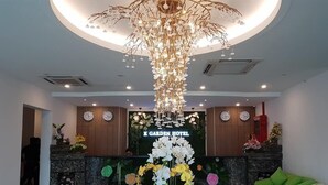Un hall d'hôtel avec un lustre moderne, une horloge et une composition florale.