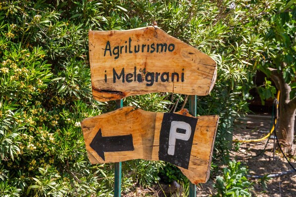 A wooden sign with 'Agriturismo i Melograni' and a parking direction arrow.