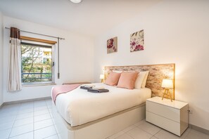 A bedroom with a bed, nightstand, and window with curtains.
