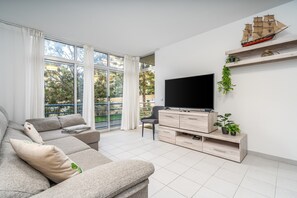 A modern living room with a sofa, TV, wooden shelves, and a balcony view. - Apartment 'Sea Breeze' with Balcony, Wi-Fi and Air Conditioning (Portimão)