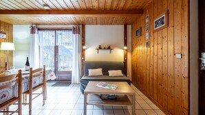 Ein Zimmer mit Holzwänden, einem Bett, einem Tisch und einem Stuhl.