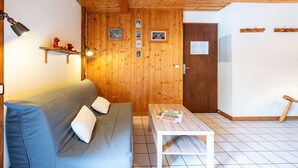 Ein Zimmer mit Holzwandverkleidung, einer Couch, einem kleinen Tisch und einer Tür.