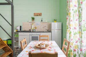 A kitchen with a dining table, chairs, a refrigerator, and a sink.