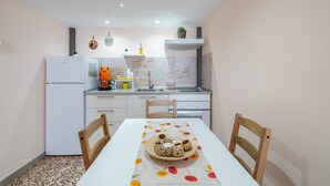 A compact kitchen with white appliances, a dining table with a floral tablecloth, and a brick backsplash.