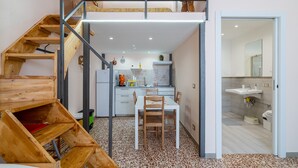 A compact kitchen with a dining area, a staircase, and a bathroom.