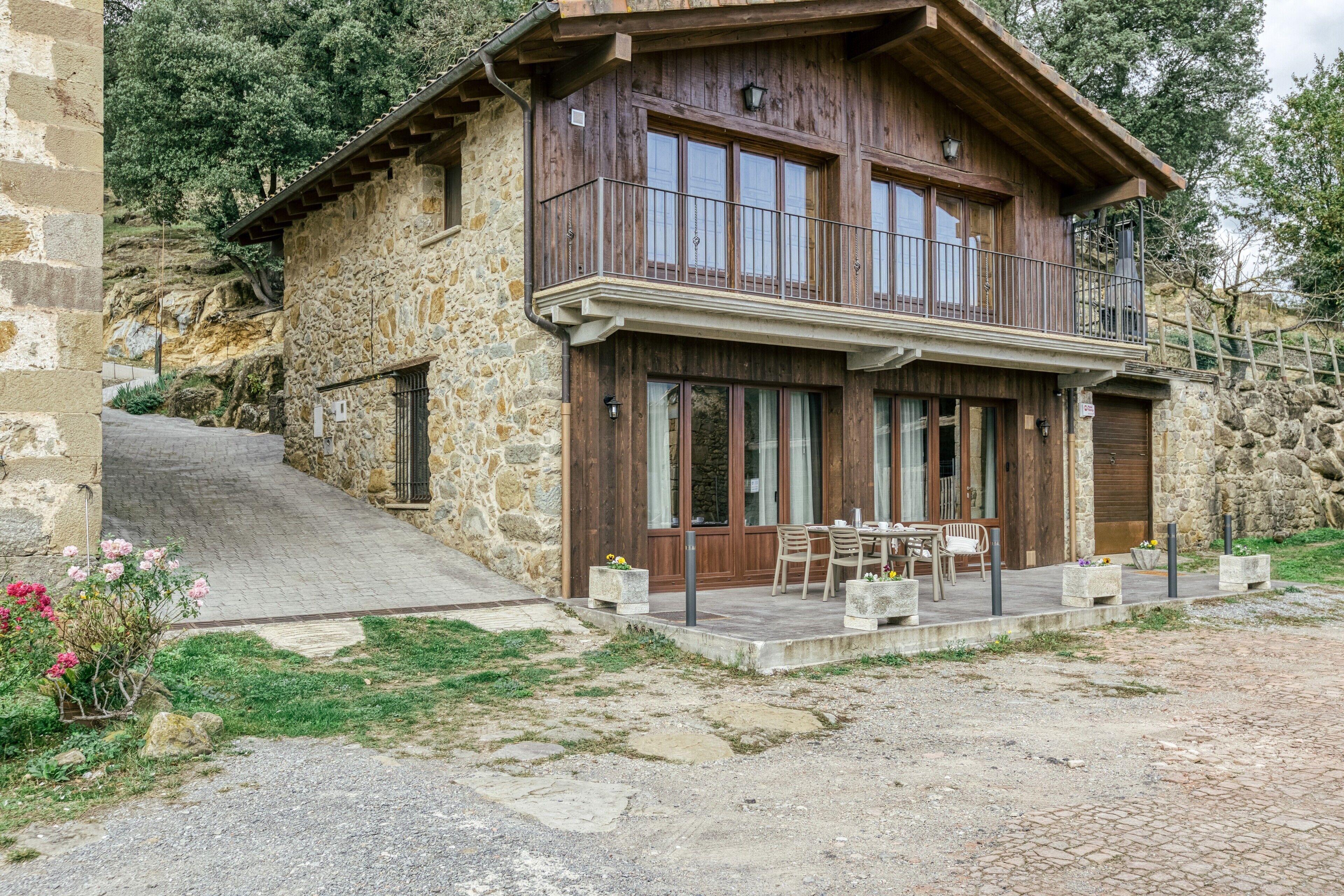 Un edificio in pietra con un balcone in legno, posti a sedere all'aperto e una scala in pietra.