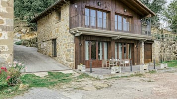 Un edificio in pietra con un balcone in legno, posti a sedere all'aperto e una scala in pietra.