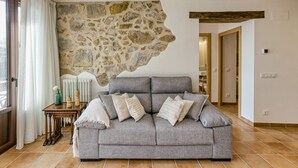 Ein Wohnzimmer mit Steinwand, grauem Sofa und Heizkörper.