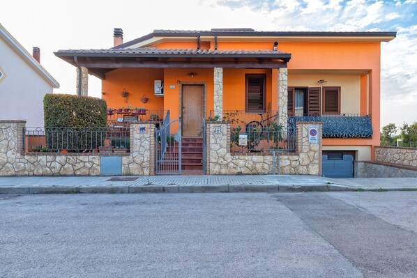 A two-story house with a stone facade, a balcony, and a gated entrance.