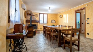A dining area with a long wooden table and chairs, a sewing machine, and a fireplace.