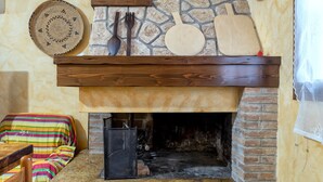 A rustic interior with a stone fireplace, wooden furniture, and a colorful striped blanket.