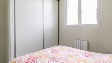 A bedroom with a bed, a window, a radiator, and a wardrobe.