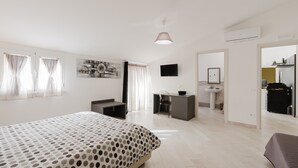 A modern hotel room with a bed, desk, chair, and a bathroom with a sink and mirror. - Room 'Camera 1' with Balcony, Wi-Fi and Air Conditioning (San Giuseppe Jato)