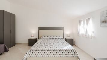 A bedroom with a bed, bedside tables, a wardrobe, and a window with curtains.