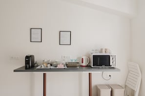 Una kitchenette equipada con cafetera, microondas, tetera y certificados enmarcados en la pared.