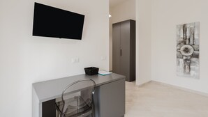 A modern room with a flat-screen TV, a desk with a chair, a cabinet, and a painting on the wall. - Room 'Camera 3' with Balcony, Wi-Fi and Air Conditioning (San Giuseppe Jato)