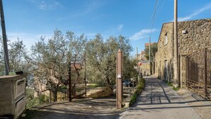 A narrow street with a metal gate, stone walls, and a clear sky.