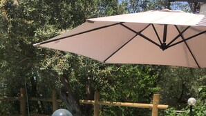 A poolside area with a pool, lounge chairs, a table, and an umbrella.