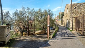 A narrow street with a gate, stone buildings, and trees.
