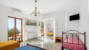 A room with a bed, a chair, a television, and a painting.