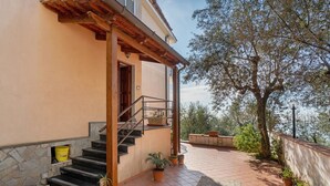 A building with a stone facade, a wooden staircase, and a tiled patio with potted plants.