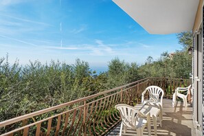 Un balcon avec une balustrade, une table avec des chaises et une vue sur les arbres et les bâtiments.