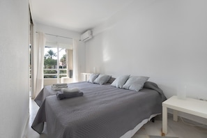 Une chambre à coucher comprenant un lit, une table de chevet, une fenêtre avec des rideaux et un appareil de climatisation.