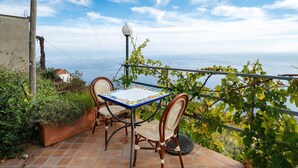 An outdoor patio with a table and chairs, overlooking a body of water and a clear sky. - Amalfi Room with Sea View (Furore)