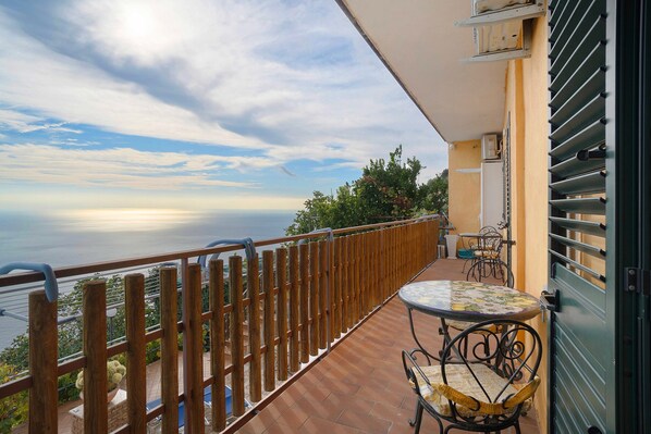 Un balcón con vista al mar, una mesa con sillas y una barandilla.