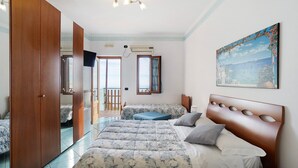 A bedroom with a bed, a wooden wardrobe, a television, and a painting on the wall. - Amalfi Room with Sea View (Furore)
