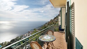 Un balcon avec une table et des chaises, offrant une vue sur la côte.