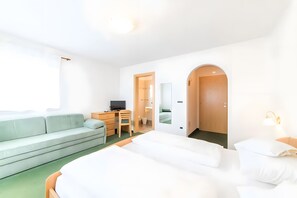 A hotel room with a bed, a sofa, a desk, a television, and a mirror.