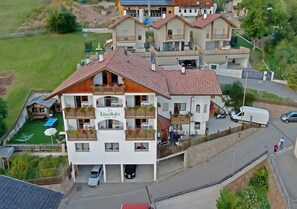 A multi-story building with balconies, a covered outdoor seating area, and a parking lot.