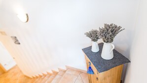 Escada que leva a um quarto com um armário de madeira e dois vasos brancos com flores secas em cima.