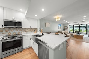 A modern kitchen with white cabinetry, stainless steel appliances, and a large island.