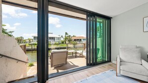 Una habitación moderna con un amplio ventanal corredera que da a una terraza exterior con piscina y sillones de descanso.