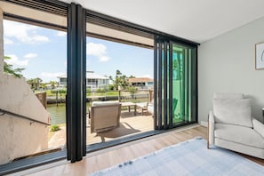 A modern room with a large sliding glass door leading to an outdoor deck with a pool and lounge chairs.
