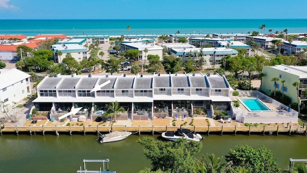 Un hotel frente al mar con piscina, varias edificaciones y un puerto deportivo.