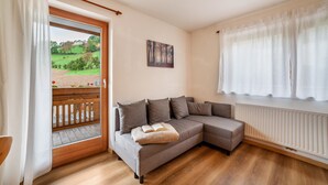 En moderne stue med en modulsofa, en radiator og udsigt til en have gennem en skydedør.
