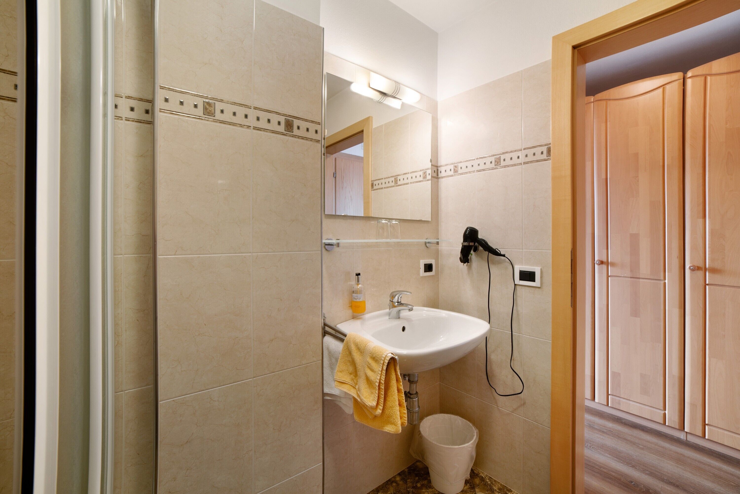 Baño con lavamanos, espejo y secador de pelo.