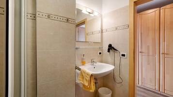 Baño con lavamanos, espejo y secador de pelo.